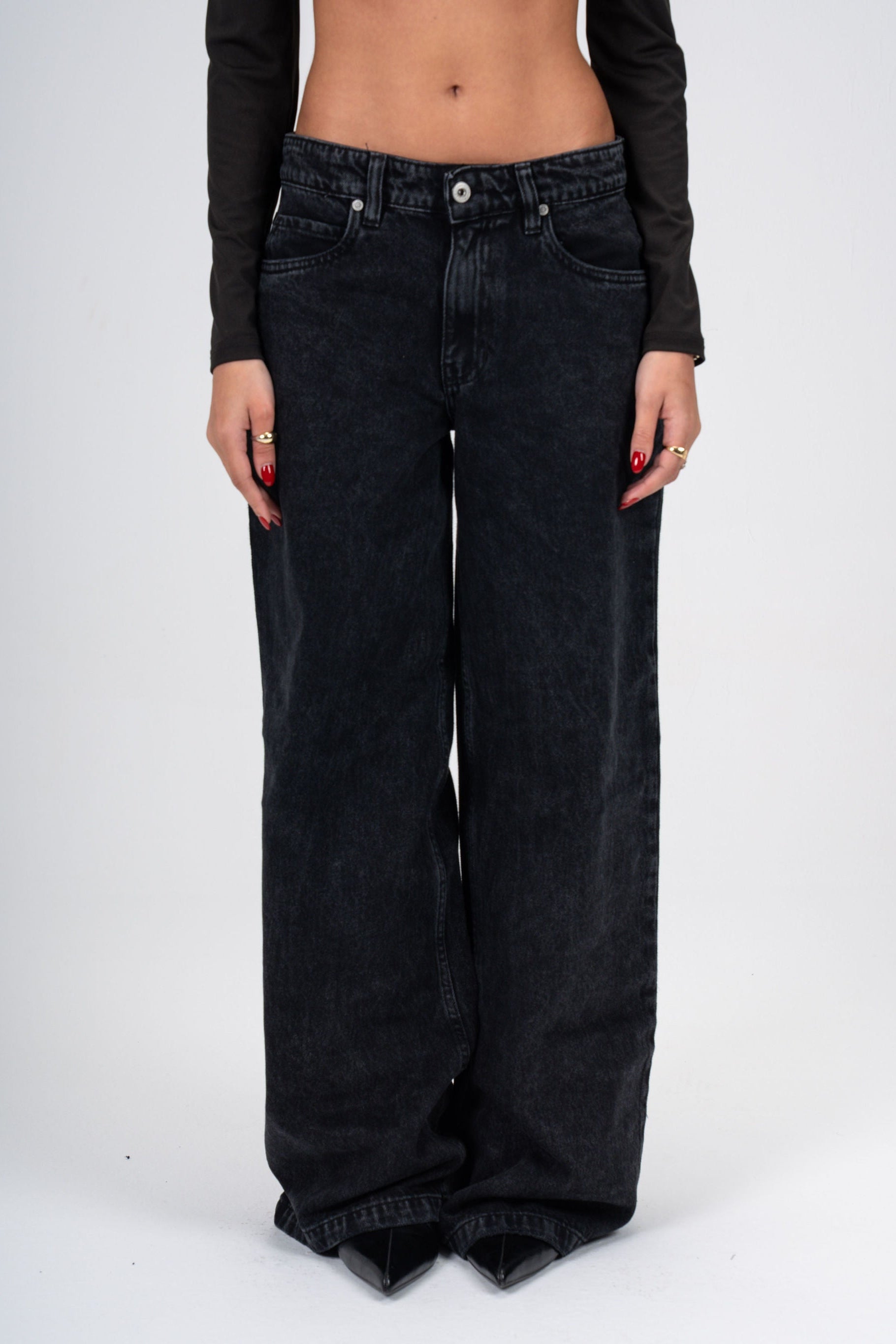 Person wearing black wide-leg jeans on a white background