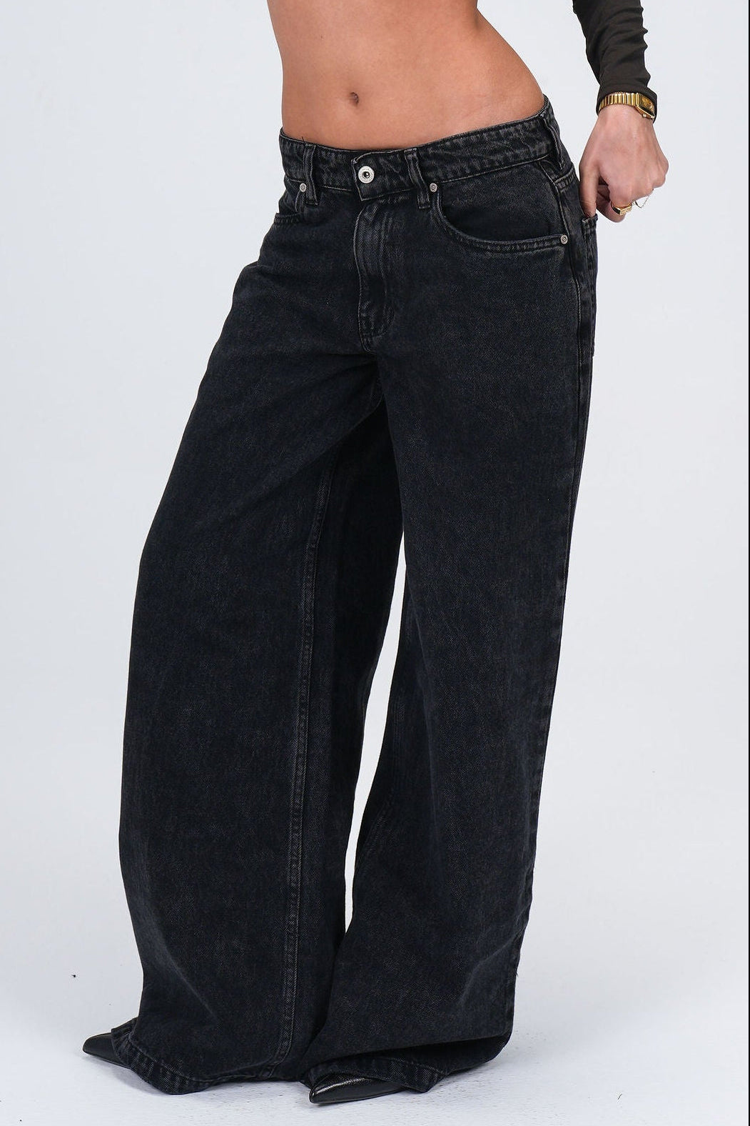 Black wide-leg jeans worn by a person on a white background