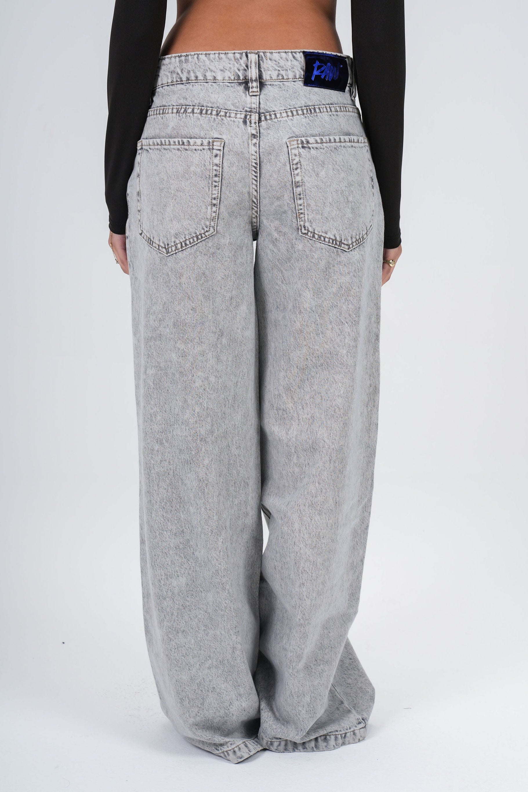 Person wearing gray wide-leg jeans on a white background