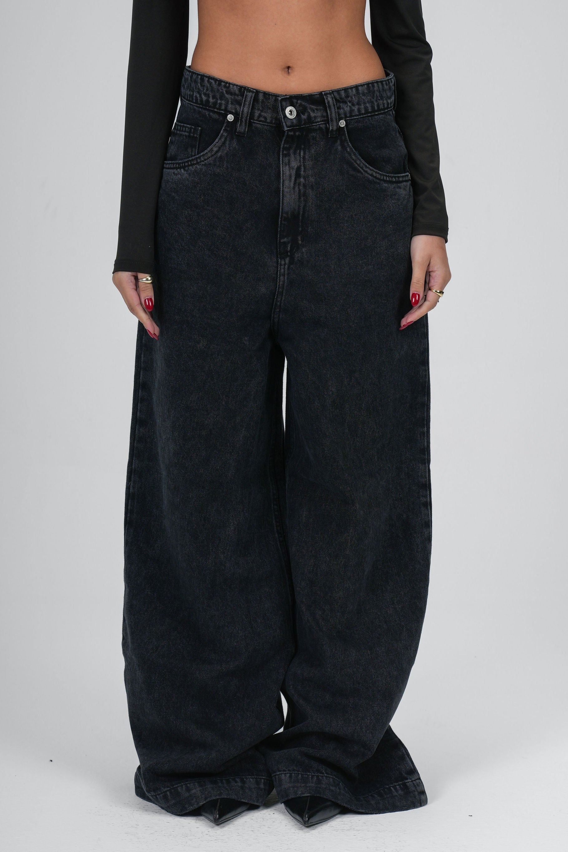 Black wide-leg jeans worn by a person on a white background
